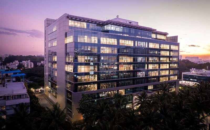A commercial glass office tower in Bangalore at dusk